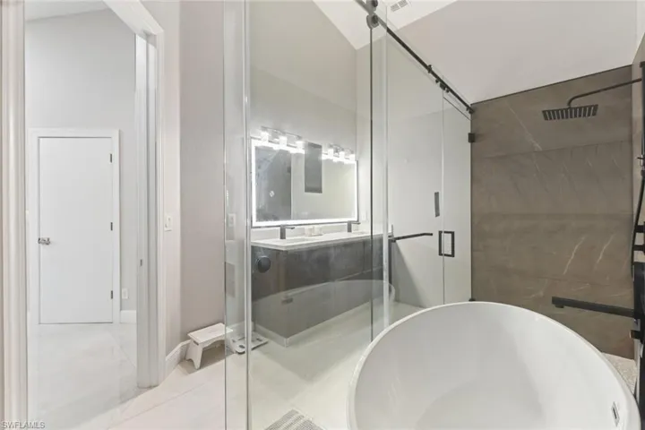 Full bathroom with a shower stall, double vanity, and a freestanding tub