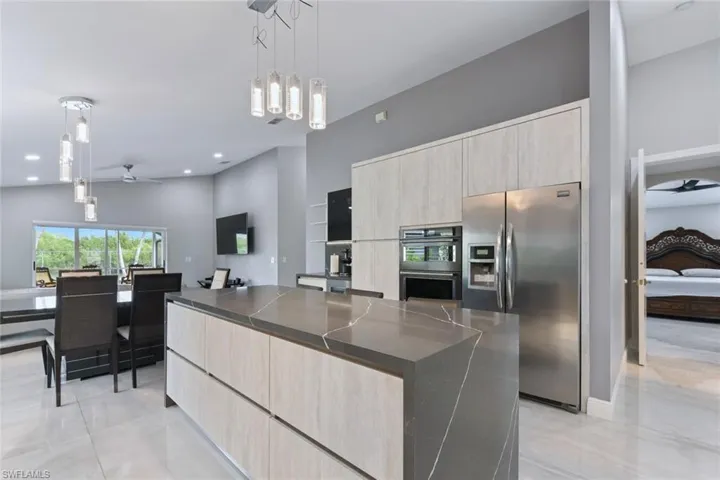 Kitchen with light wood finish cabinets, ceiling fan, decorative light fixtures, and stainless steel appliances