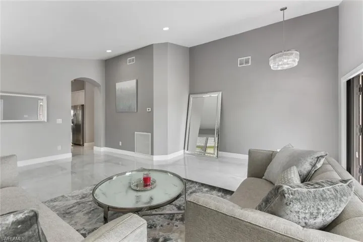 Living room featuring arched walkways, a high ceiling, and recessed lighting