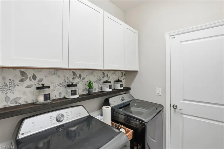 Washroom featuring washing machine and clothes dryer and cabinet space