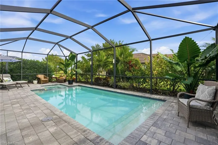 View of pool with glass enclosure and a pool with connected hot tub