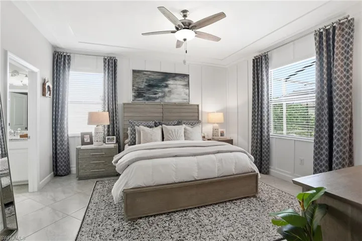 Bedroom featuring a decorative wall, a ceiling fan, light tile patterned flooring, and connected bathroom