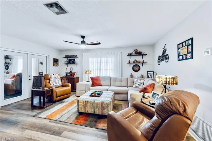 Living room with ceiling fan, french doors, a textured ceiling, and hardwood / wood-style flooring