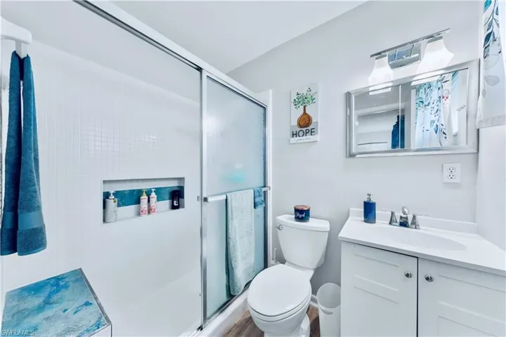 Bathroom with hardwood / wood-style floors, vanity, toilet, and walk in shower