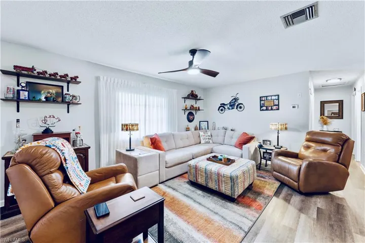Living room with ceiling fan, wood-type flooring, and a textured ceiling