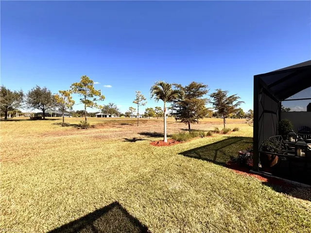 View of grassy yard with glass enclosure and a sunroom
