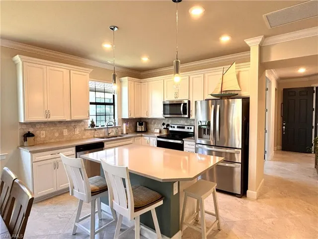 Kitchen featuring crown molding, stainless steel appliances, a kitchen island, a breakfast bar area, and pendant lighting