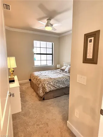 Bedroom featuring light carpet, crown molding, and a ceiling fan