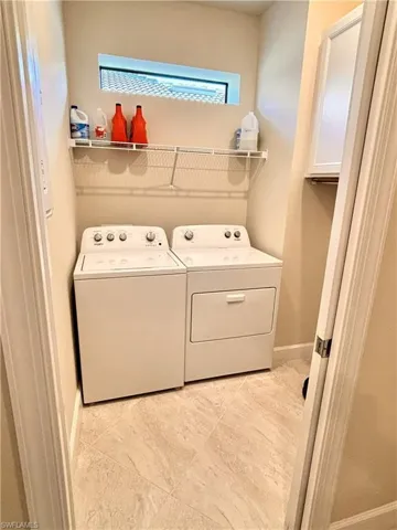 Laundry area with separate washer and dryer and baseboards
