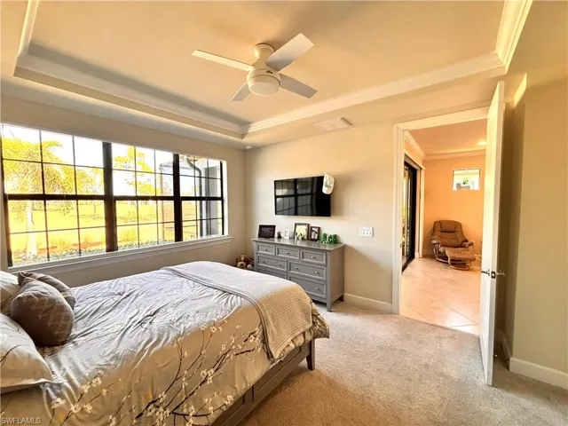 Bedroom with carpet, a ceiling fan, crown molding, and a tray ceiling