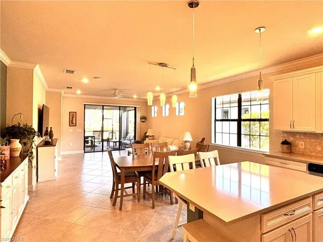 Kitchen featuring crown molding, decorative light fixtures, open floor plan, a kitchen island, and dark stone countertops