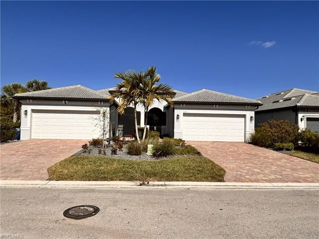 Ranch-style house featuring a tile roof, stucco siding, driveway, and a garage