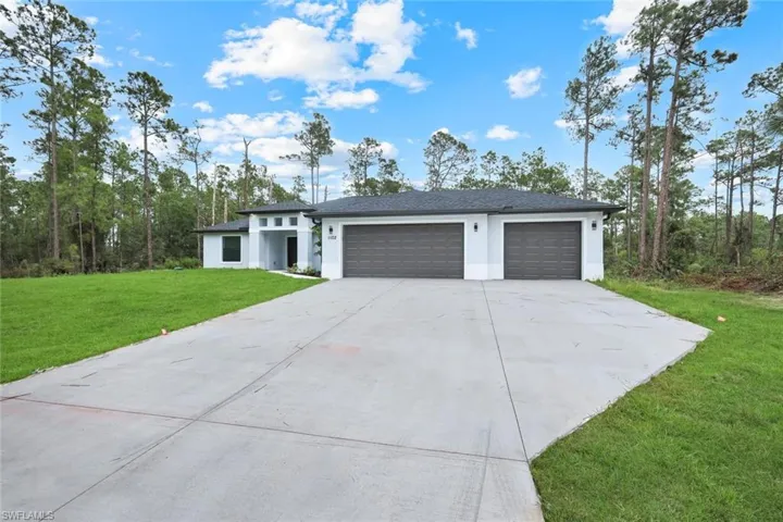 View of front of property featuring a front yard, driveway, a garage, and stucco siding