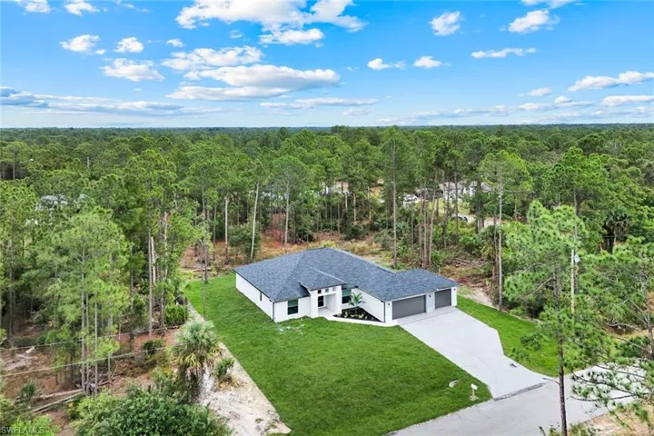 Aerial view of property and surrounding area featuring a forest