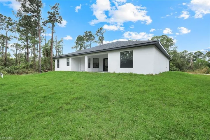 Back of property featuring a patio, a lawn, and stucco siding