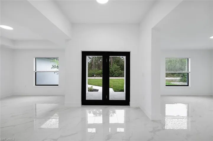 Entrance foyer with light marble finish floors and recessed lighting view towards large front impact glass front door - living room to one side dinning room on the other - either room can be a flex space
