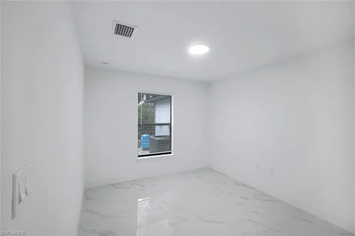 Unfurnished room featuring baseboards and light marble finish floors