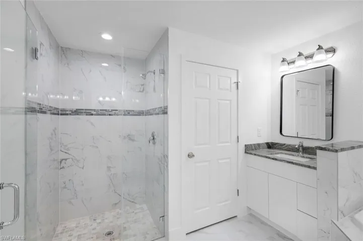 Primary bathroom featuring graite vanity, light marble finish floors, a beautiful tiled large shower, and recessed lighting