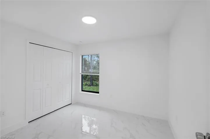 Bedroom 3 featuring light marble finish floors and a closet