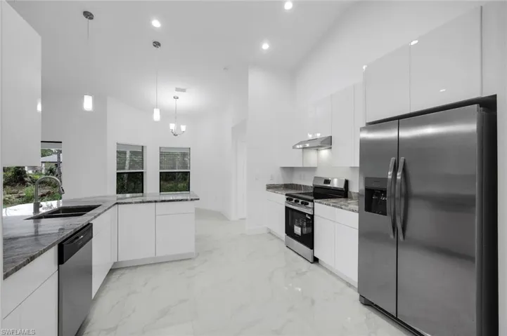 Kitchen with stainless steel appliances, pendant lighting, granite counters, modern cabinets, and a high ceiling