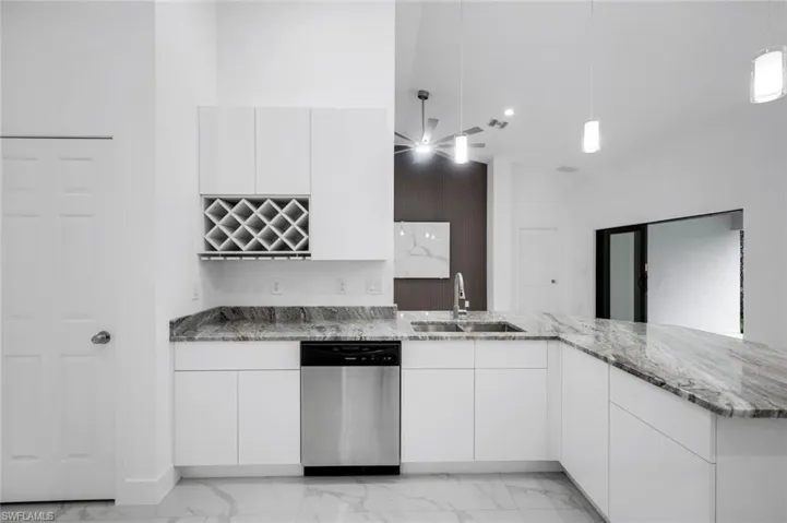 Kitchen with white cabinets, stainless steel dishwasher, decorative light fixtures, modern cabinets, and granite counters,  pendants lights and wine rack