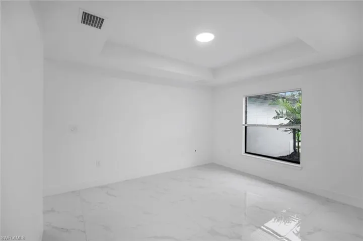Spare room featuring light marble finish floors, a tray ceiling, and recessed lighting