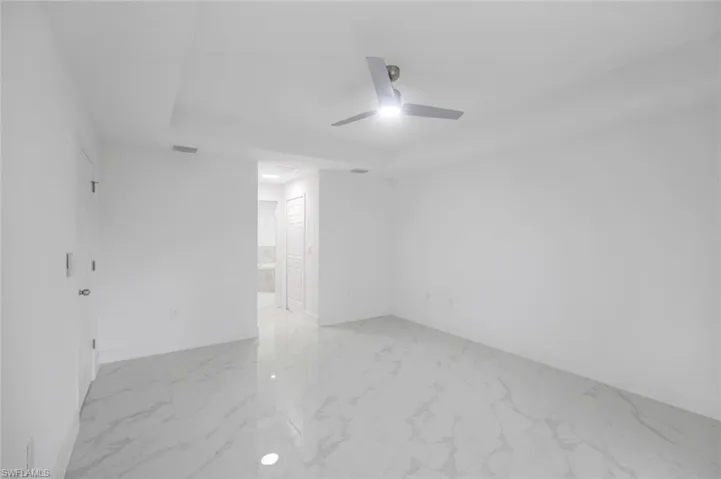 Primary bedroom featuring light marble finish flooring a ceiling fan and  2 walk in closets