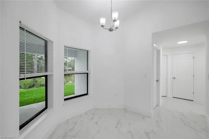 Dinette Area with large impact windows,  marble finish flooring and a chandelier