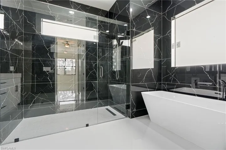 Bathroom with plenty of natural light, tile walls, and independent shower and bath