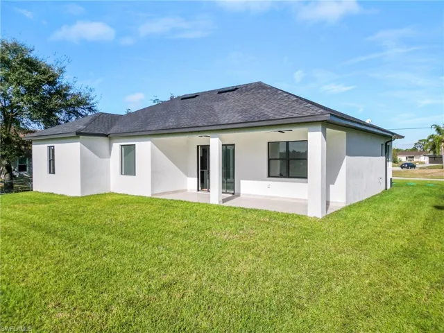 Back of property featuring ceiling fan, a yard, and a patio