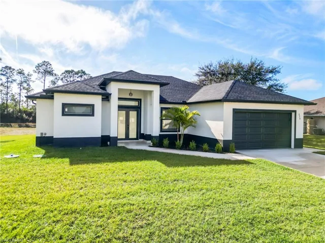 View of front of property featuring french doors, a front lawn, and a garage
