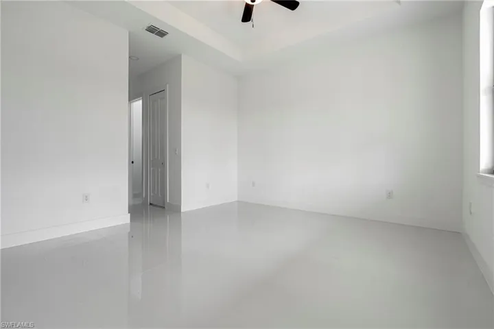 Tiled empty room featuring a raised ceiling and ceiling fan