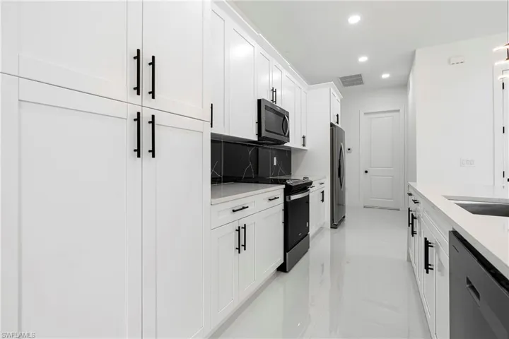 Kitchen featuring tasteful backsplash, sink, white cabinets, and appliances with stainless steel finishes