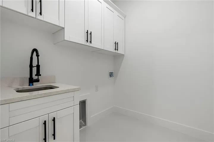 Clothes washing area featuring cabinets, sink, and hookup for a washing machine