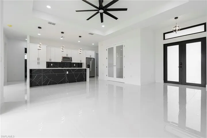 Unfurnished living room with ceiling fan, a tray ceiling, and french doors