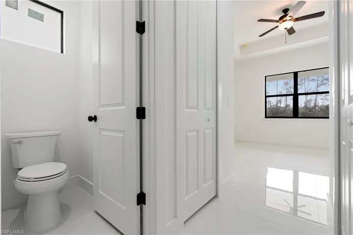 Bathroom featuring tile patterned floors, toilet, and ceiling fan