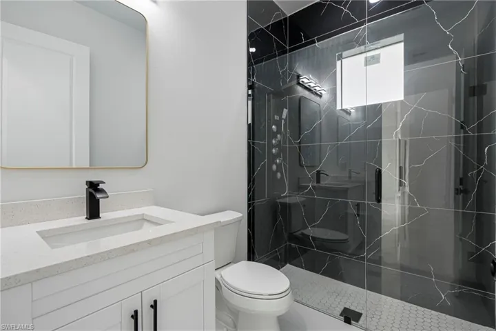 Bathroom with vanity, toilet, and a shower with door