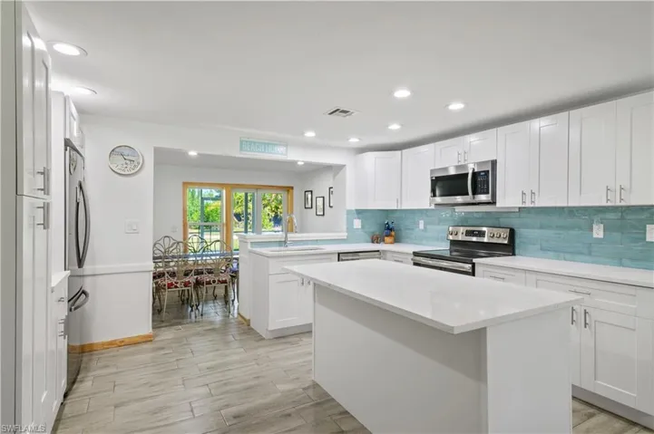 Kitchen with visible vents, backsplash, a peninsula, stainless steel appliances, and a sink