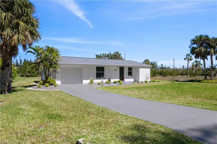 Ranch-style house featuring a front yard, a garage, driveway, and stucco siding