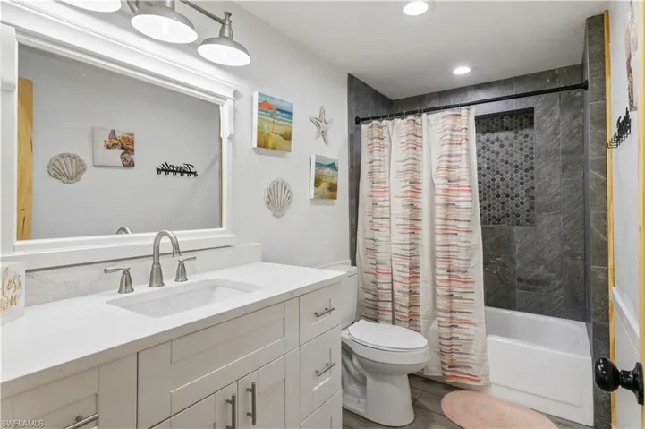 Bathroom featuring recessed lighting, toilet, shower / bath combo, and vanity