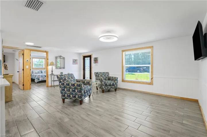 Sitting room featuring visible vents, wainscoting, and light wood-style floors