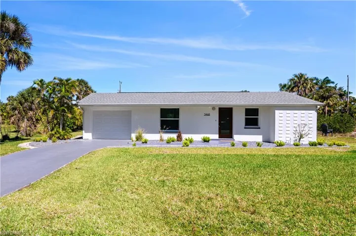 Ranch-style house featuring a garage, driveway, a front lawn, and stucco siding