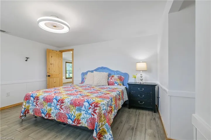 Bedroom featuring visible vents, wainscoting, and wood finished floors