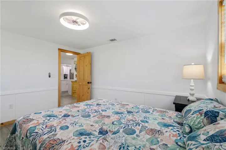 Bedroom featuring a wainscoted wall, a decorative wall, and visible vents