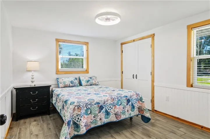 Bedroom featuring a wainscoted wall, multiple windows, and light wood-style floors