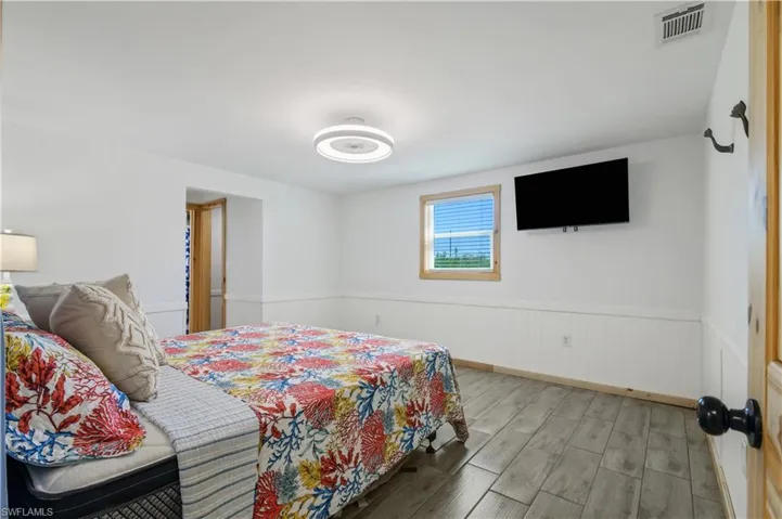Bedroom featuring visible vents, wood finished floors, and wainscoting