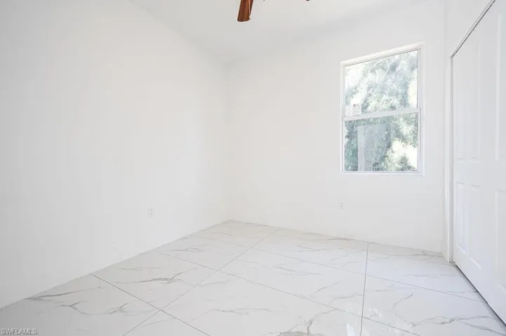 Spare room with light marble finish flooring and a ceiling fan. Photos are of a staged model or similar plan. Features and finishes may vary.
