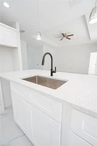 Kitchen featuring white cabinets, pendant lighting, a tray ceiling, and recessed lighting. Photos are of a staged model or similar plan. Features and finishes may vary.