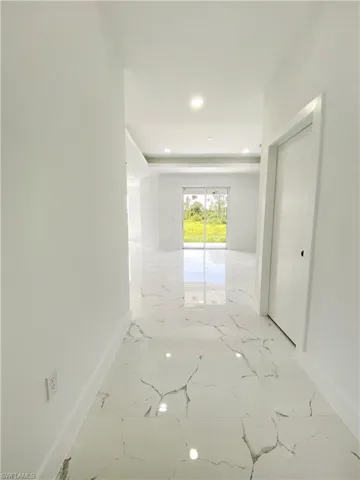 Hallway featuring light marble finish floors, recessed lighting, and a raised ceiling. Photos are of a staged model or similar plan. Features and finishes may vary.