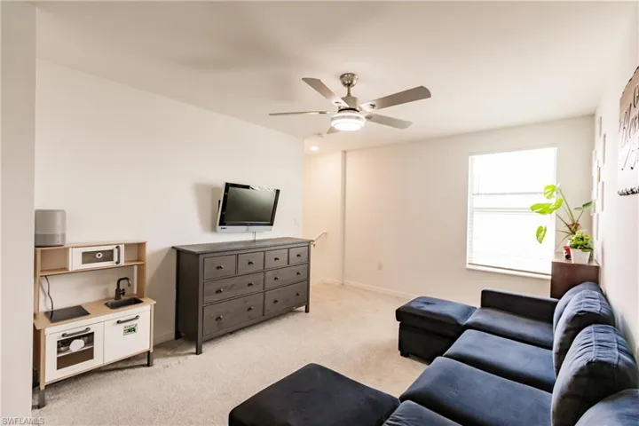 Carpeted living room with ceiling fan